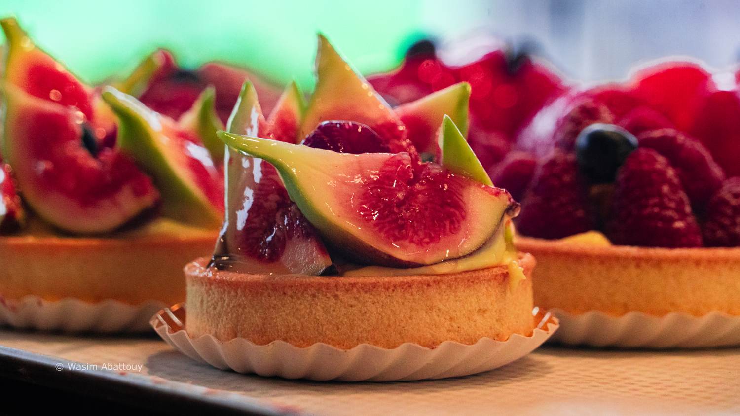 A fig tart with red berries on a bakery counter