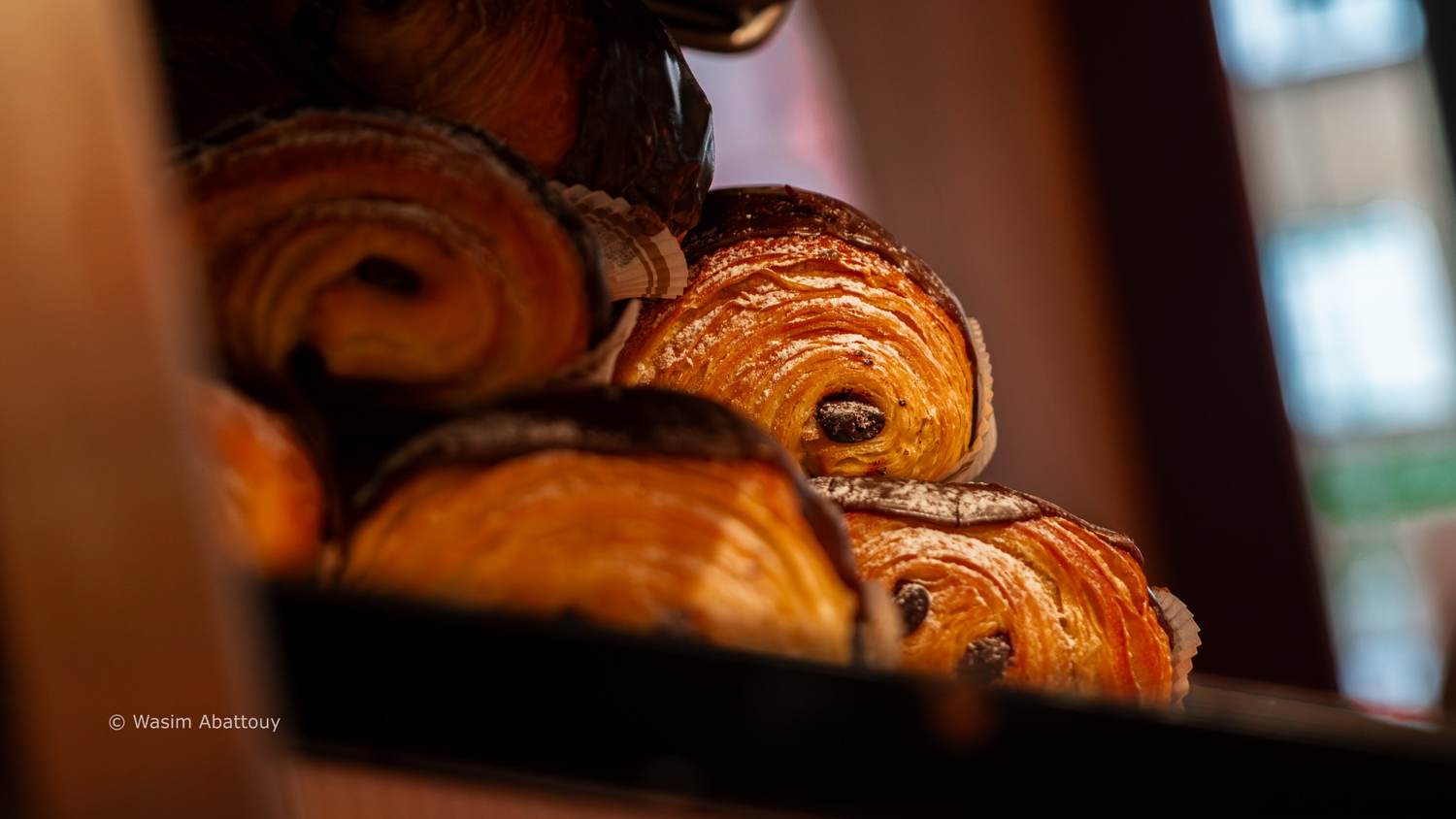 Pains au chocolat stacked on a tray, lit from the side