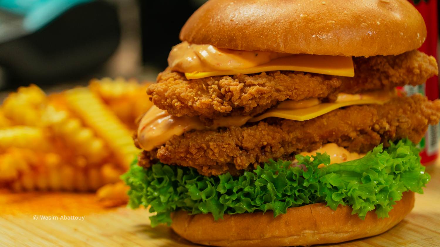 Double crispy chicken burger with cheese and lettuce on a wooden board