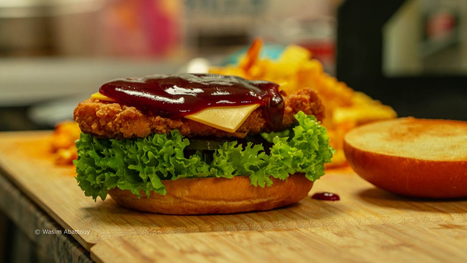 Open crispy chicken burger with barbecue sauce and cheese on a wooden board