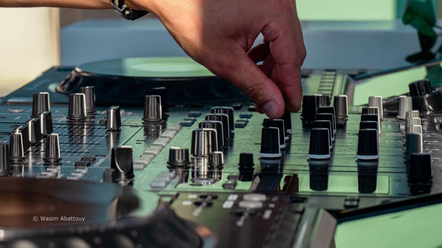 Close-up of a hand turning knobs on a DJ mixer