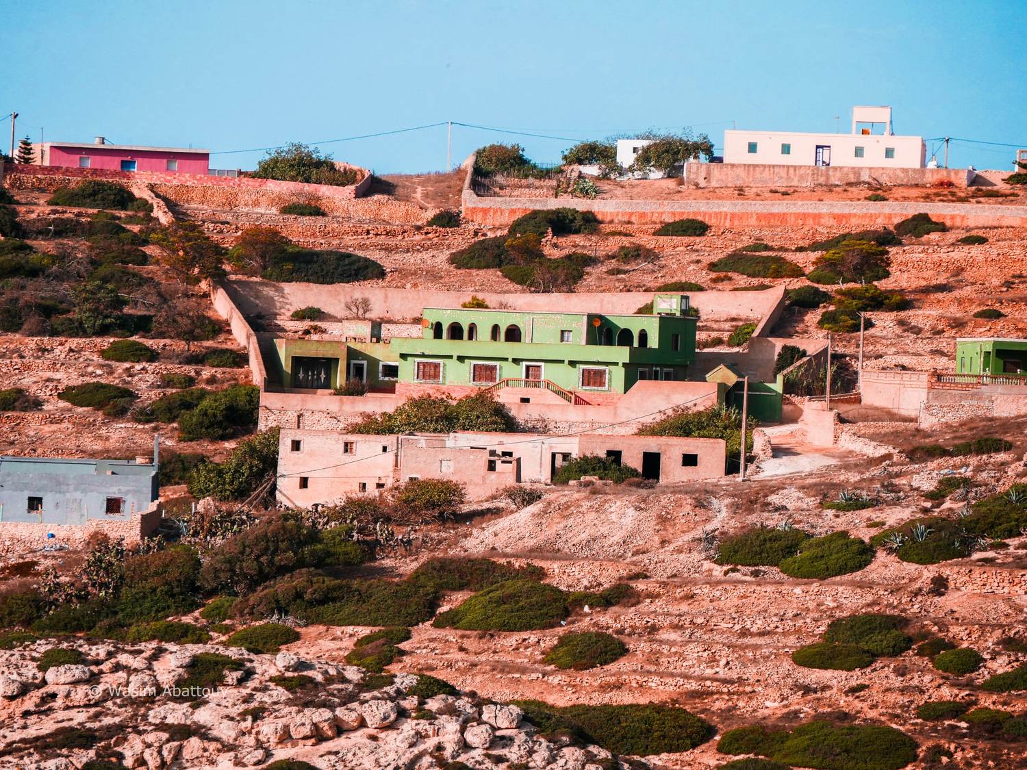 Houses and green villa on terraced hillside with stone walls